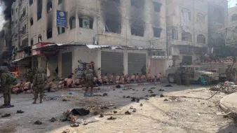 Scène de rue sombre avec des personnes assises et des soldats armés. Atmosphère tendue.