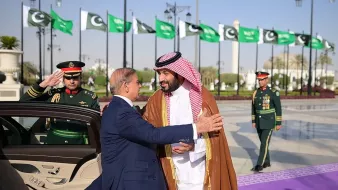 لقاء رسمي بين قائدين، مع أعلام وموظفين عسكريين في الخلفية.