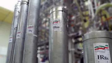 در این تصویر تعدادی سیلندر استوانه‌ای فلزی دیده می‌شود که بر روی آن‌ها برچسب‌هایی با نام «IR8» و «IR8b» قرار دارد. سیلندرها در یک محیط صنعتی یا آزمایشگاهی قرار دارند که نشان‌دهنده تجهیزات مربوط به فرآیندهایی مانند غنی‌سازی اورانیوم هستند. در پس‌زمینه، دستگاه‌ها و لوله‌های دیگری هم وجود دارد که نشان‌دهنده پیشرفت‌های فناوری در این زمینه است. رنگ پرچم ایران نیز بر روی برچسب‌ها قابل مشاهده است.
