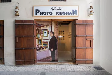 Une porte en bois s'ouvre sur une galerie photo avec des images exposées.