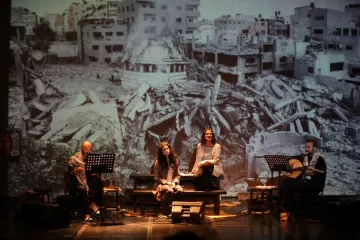 Quatre artistes sur scène, avec une projection d'un paysage de destruction en arrière-plan.