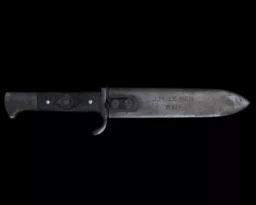 Un couteau avec une lame métallique et un manche noir, gravé d'inscriptions.