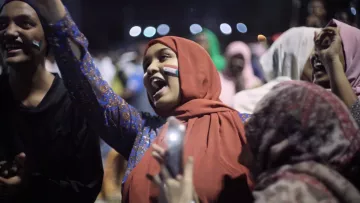 Groupe de jeunes célébrant avec enthousiasme, drapeaux et sourires.