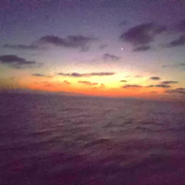 Un coucher de soleil aux couleurs chaudes se reflète sur la mer calme.