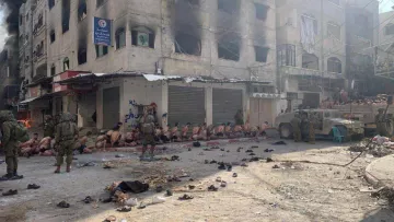 A scene of distress showing people detained in an urban setting with military presence.