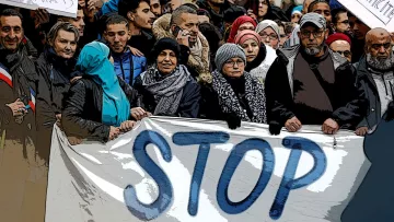 The image depicts a large group of people gathered together, holding a banner that prominently features the word "STOP." The individuals are dressed in various winter attire, including scarves and jackets, suggesting it may be cold. Some in the crowd appear to be wearing traditional clothing or head coverings. The atmosphere seems to convey a sense of unity and purpose, likely indicating a collective protest or demonstration. There are additional signs raised around the crowd, emphasizing their message.