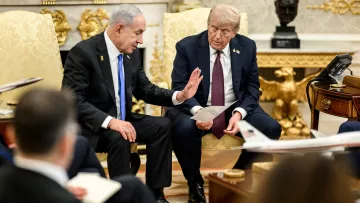 Deux hommes en costume discutent assis dans un bureau au mobilier élégant.