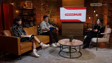 Trois personnes discutent dans un salon moderne, avec un écran au fond.