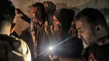 A group of people in a dim space, some worried, holding cell phone lights in tense expressions.