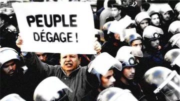 L'image montre une scène de manifestation où un homme tient une grande pancarte avec l'inscription "PEUPLE DÉGAGE !" Au premier plan, cet homme semble déterminé et engagé, tandis qu'en arrière-plan, un groupe de policiers en uniforme avec des casques se tient à proximité, suggérant une tension entre les manifestants et les forces de l'ordre. L'atmosphère semble chargée d'émotion et de revendication.