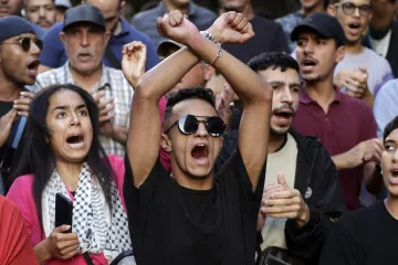 Groupe de manifestants exprimant des émotions fortes, certains brandissant les bras.