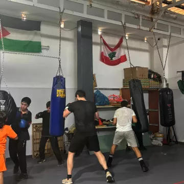 Un groupe de boxeurs s'entraîne dans une salle avec des sacs de frappe.