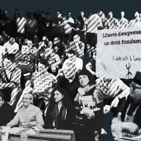 A diverse crowd of people sits in protest, holding signs advocating for freedom of expression.