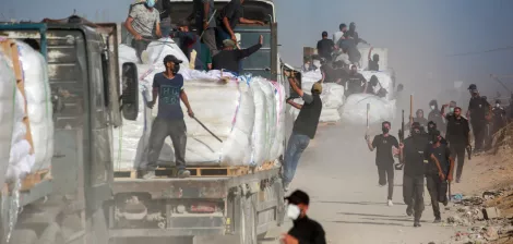 Des camions chargés de marchandises, des travailleurs en mouvement dans la poussière.
