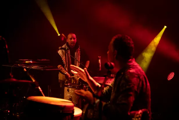 Deux musiciens sur scène, illuminés par des lumières rouges, jouant des percussions.
