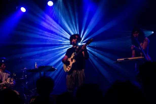 Concert vibrant avec un musicien à la guitare, entouré de lumières rayonnantes.