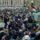Un grand rassemblement de manifestants avec des drapeaux, dans un parc.