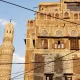 Vieilles maisons en briques, motifs géométriques, minaret élancé sous un ciel bleu.