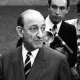 Deux hommes en costume, discutant sérieusement, entourés d'autres personnes. Époque rétro.