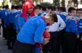 Des jeunes scouts en chemises bleues, certains portent des foulards rouges, se regroupent.
