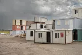 Des bâtiments modulaires colorés, regroupés sur un terrain sous un ciel nuageux.