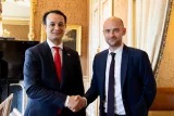 Deux hommes sourient en se serrant la main dans un cadre élégant.