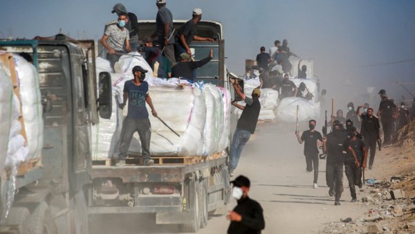 Des camions chargés de marchandises, des travailleurs en mouvement dans la poussière.