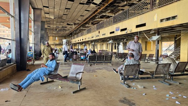 Gare désertée avec des bancs usés et des passagers attendant, ambiance de désolation.
