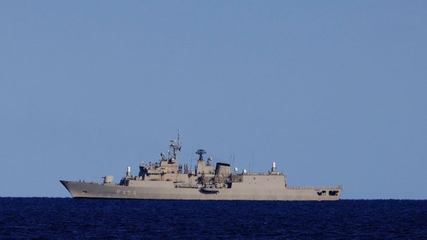 Un navire militaire gris flotte sur une mer calme, sous un ciel dégagé.