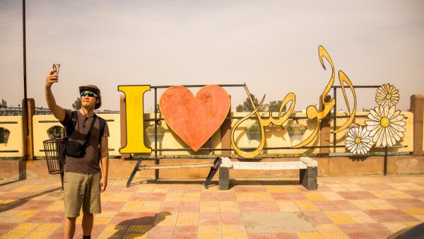 Un homme prend un selfie devant une grande inscription colorée 