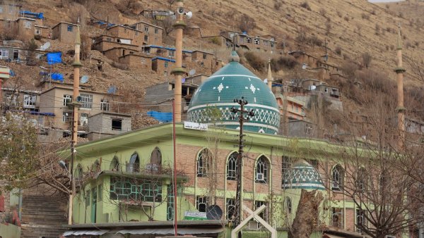 Un bâtiment avec un toit en dôme vert, entouré de collines et de maisons.