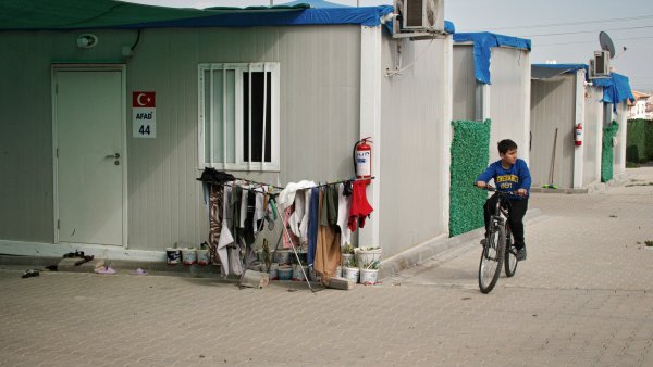 Un enfant à vélo passe près de cabines modulaires et de vêtements accrochés.