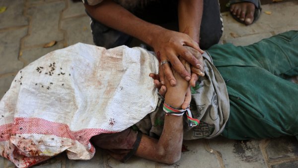 Une personne blessée, allongée au sol, entourée de mains qui l'aident.