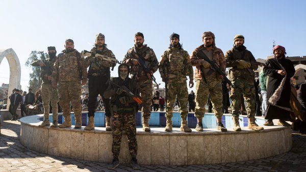 Huit hommes armés, posant ensemble devant un bassin, ciel clair en arrière-plan.