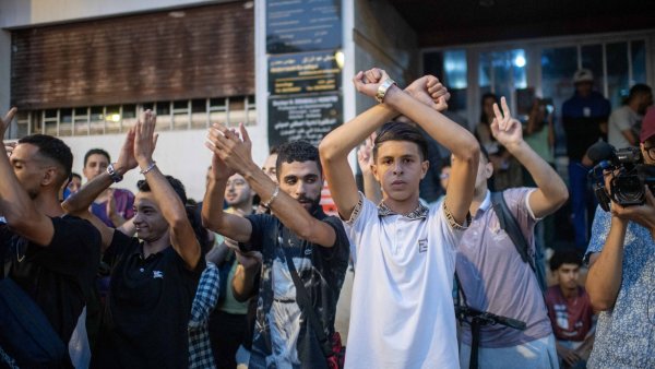 Un groupe de jeunes applaudit et fait des gestes de soutien lors d'un événement.
