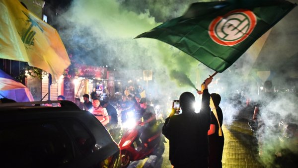 Des manifestants brandissent des drapeaux sous une fumée colorée dans une ambiance festive.