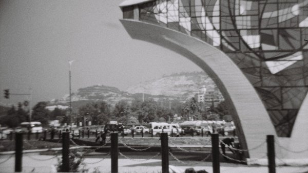 Une architecture moderne avec des formes curvilignes, entourée de voitures et de verdure.