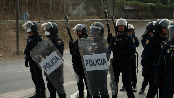 Des policiers en tenue, boucliers transparents et casques, prêts à intervenir.