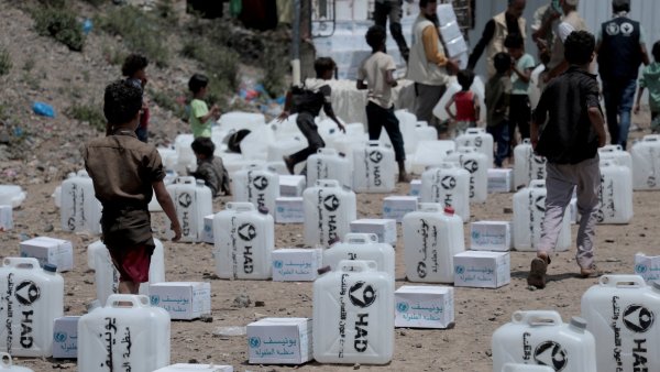 Des enfants jouent près de boîtes de fournitures humanitaires dans un camp.