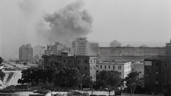 Une ville sous un ciel brumeux, avec de la fumée s'élevant d'un immeuble.