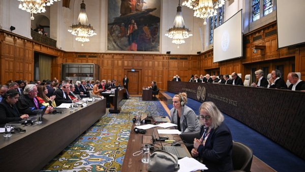 Salle d'audience avec de nombreux avocats, juges et un grand tableau mural.