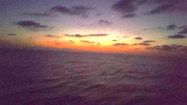 Un coucher de soleil aux couleurs chaudes se reflète sur la mer calme.