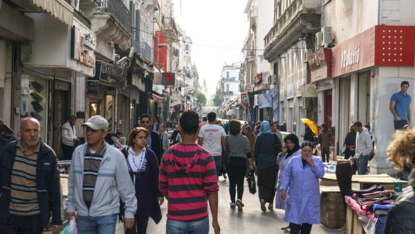 Une rue animée avec des passants, boutiques et bâtiments typiques.