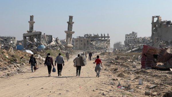 Un paysage dévasté avec des bâtiments détruits et des personnes marchant sur une route.