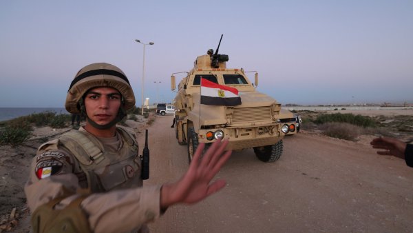 Un soldat égyptien lève la main près d'un véhicule militaire équipé.