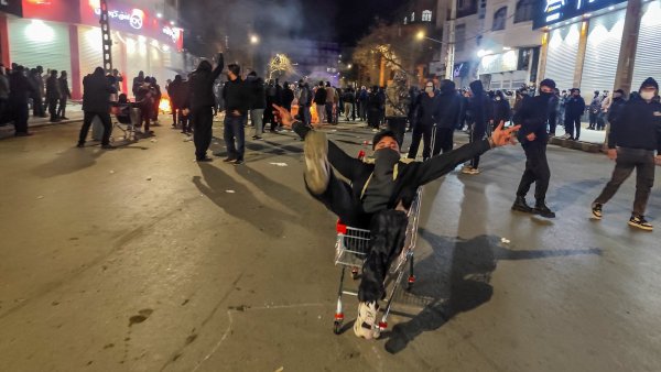 Un homme dans un caddie, entouré d'une foule en mouvement dans une rue animée.