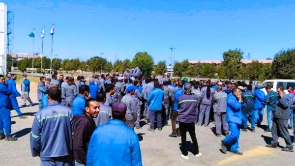Un groupe d'hommes en uniforme discute dans un espace extérieur ensoleillé.